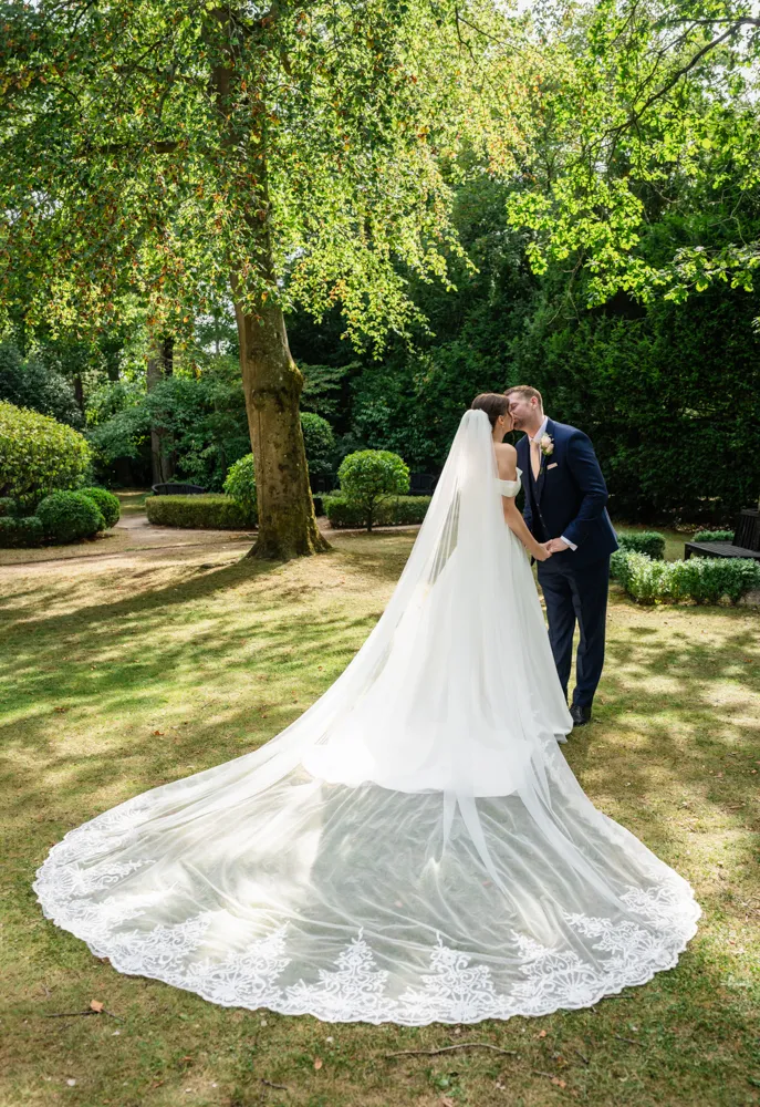 Bride and groom kiss In the gardens of The Bull Hotel in Gerrards Cross on their August wedding day. Bull Hotel Wedding Photographer.