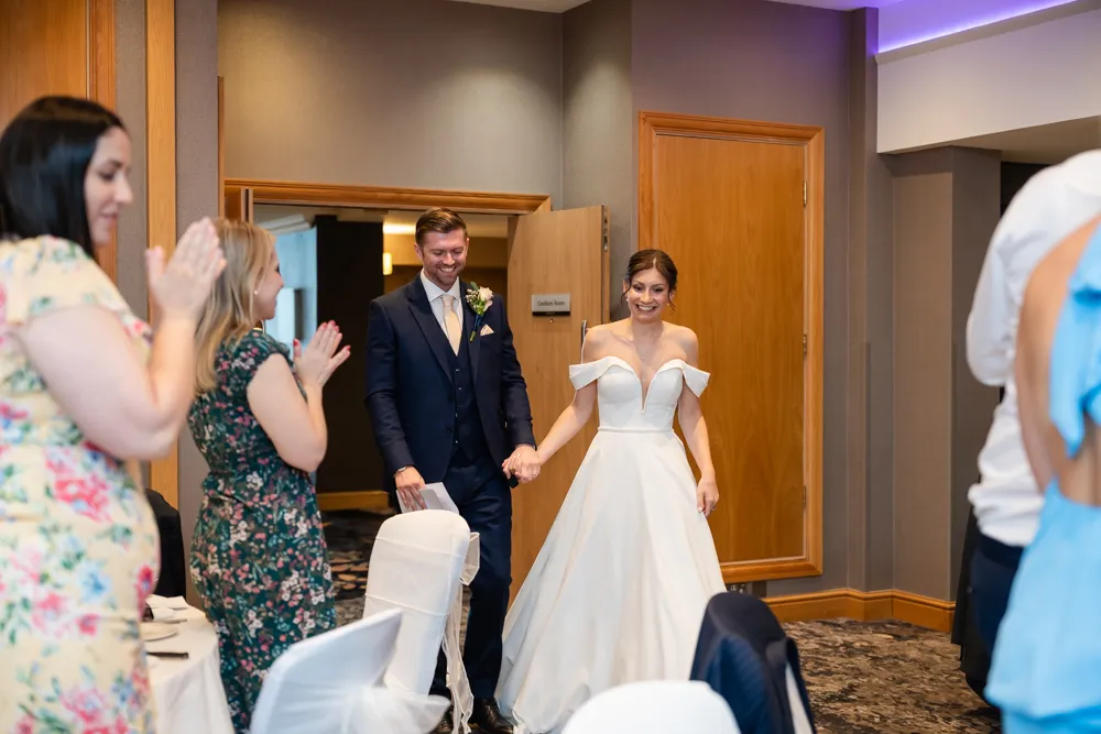 Bride and groom enter their wedding breakfast in the Thames Suite. Bull Hotel Wedding Photographer.