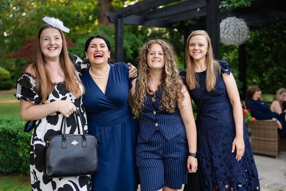 Guests laughing in Bull Hotel gardens in Gerrards Cross. Bull Hotel Wedding Photographer.