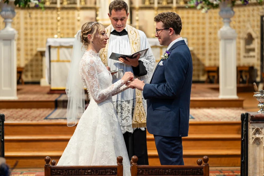 Oxford Oratory wedding photographer. Bride and groom exchange rings during wedding ceremony.