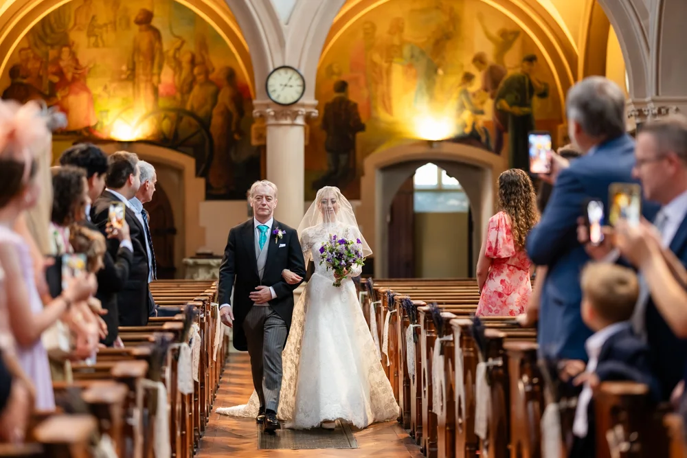 Oxford Oratory wedding photographer. Bride walks down the aisle with her father.