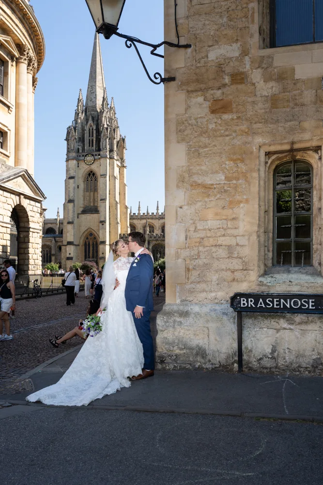 Oxford University wedding photographer. Bride and groom kiss on corner of Brasenose Lane in Radcliffe Square.