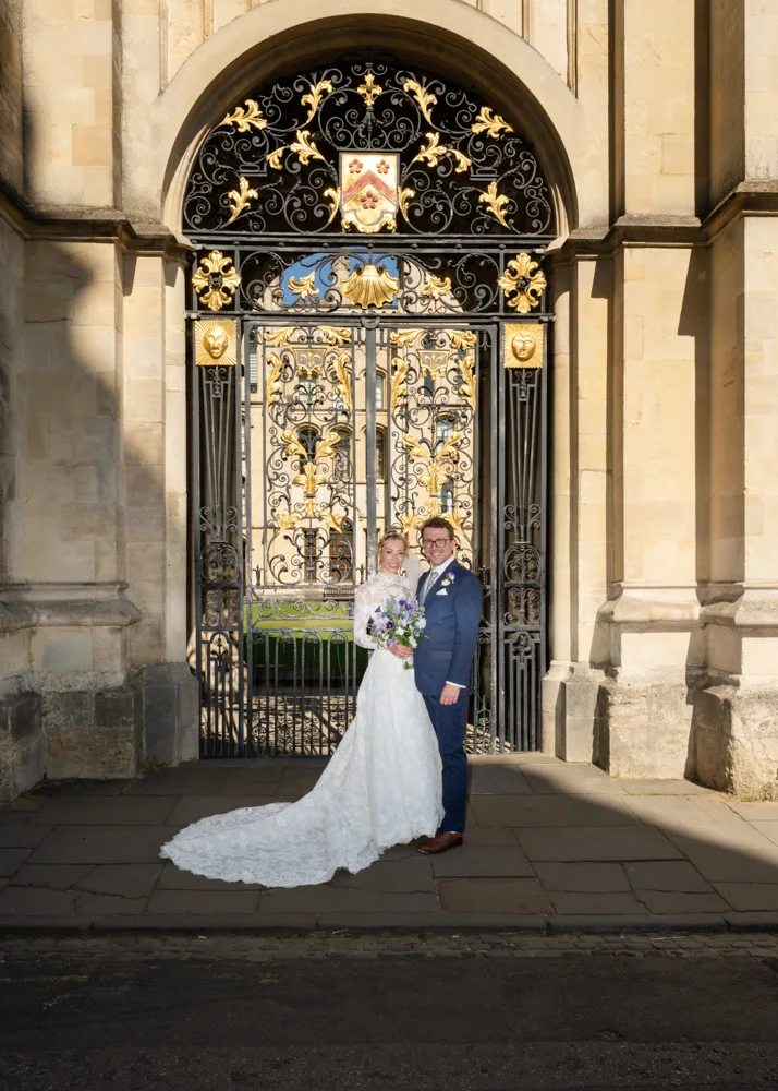 Oxford University wedding photographer with newlyweds outside Old Souls College gate in Radcliffe Square
