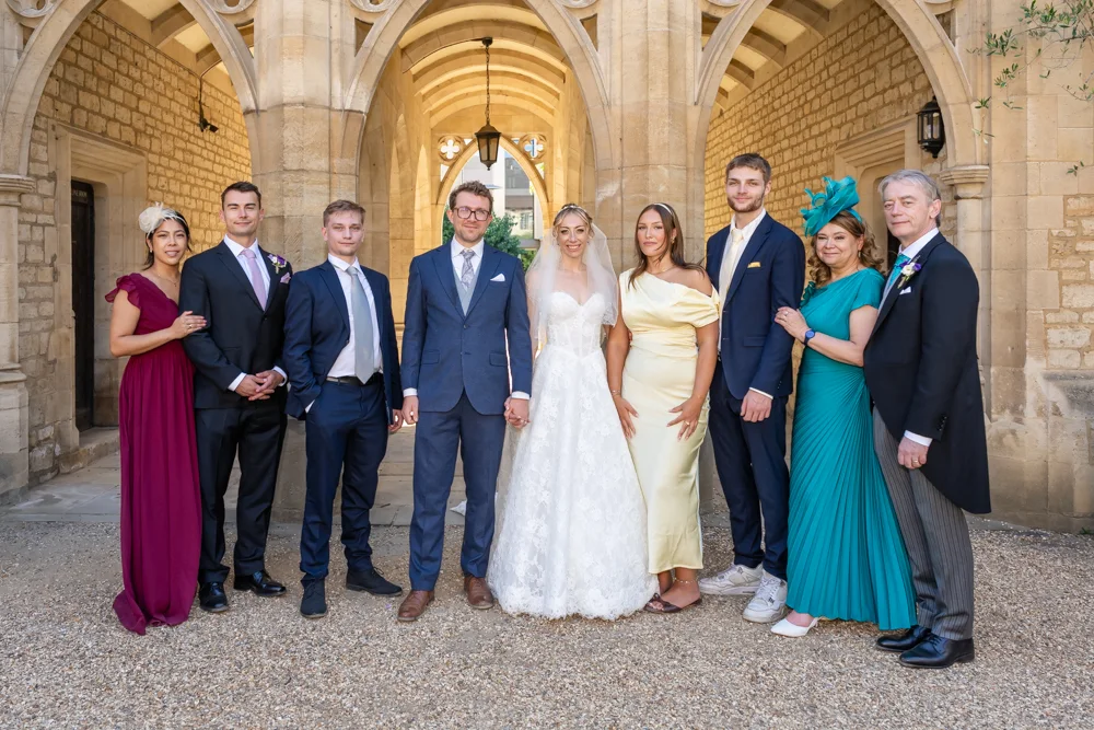 St Cross College wedding photographer. Bride and groom with family in front of four colleges arches.