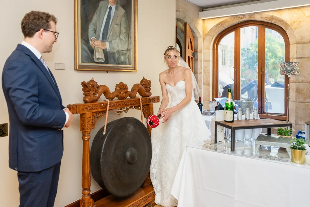 St Cross College wedding photographer. Bride and groom striking dinner gong.