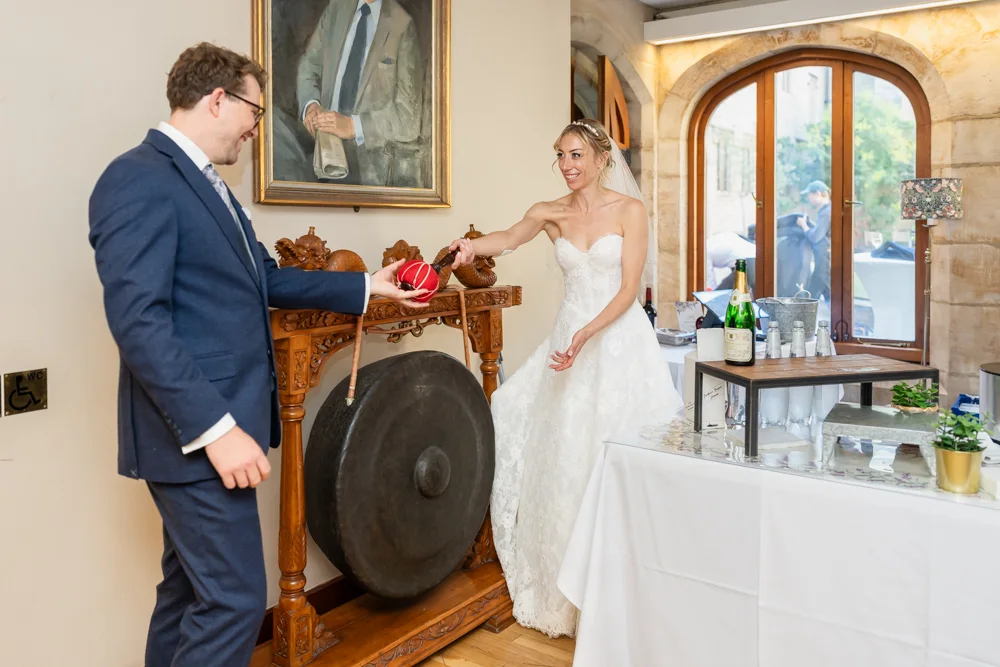 St Cross College wedding photographer. Bride and groom striking dinner gong.